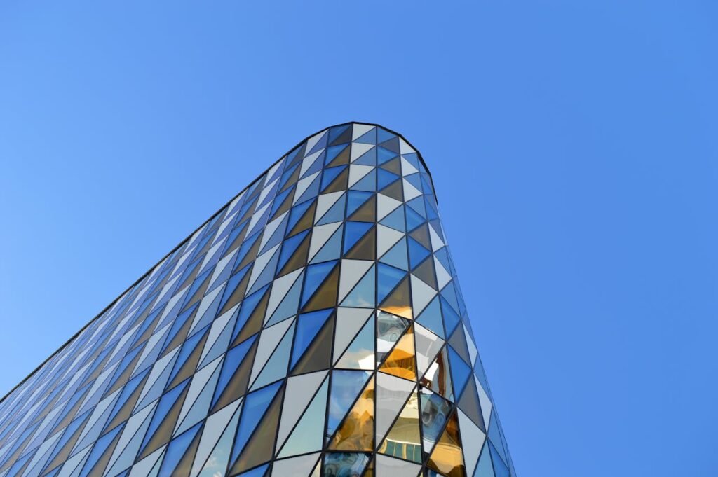 A modern building with a geometric glass facade under a clear blue sky in Hagalund, Sweden.