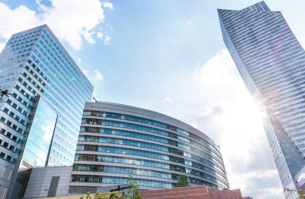 Urban cityscape with modern skyscrapers reflecting sunlight against a blue sky.